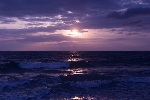 日落期间的蓝色海洋和乌云的照片 · 免费素材图片