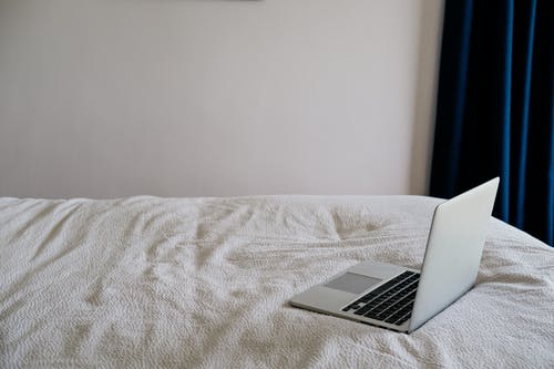 在家里的软皱巴巴的床上打开笔记本电脑 · 免费素材图片
