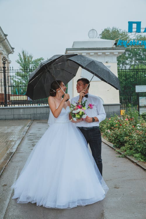 性格开朗的新婚夫妇站在雨下 · 免费素材图片