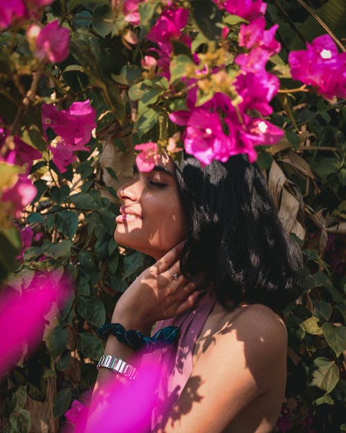 女人站在粉红色的花朵附近的照片 · 免费素材图片