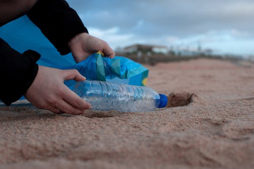 持有透明塑料瓶的人 · 免费素材图片