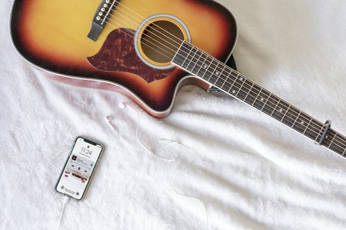 智能手机旁边的红色和黑色民谣吉他 · 免费素材图片