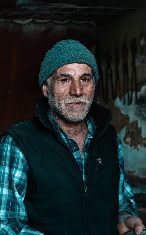 戴无檐小便帽帽子的蓝色夹克的老人的肖像照片 · 免费素材图片
