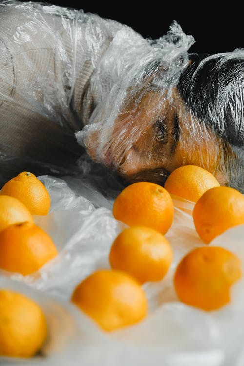 在女人面前的橙色水果覆盖着塑料 · 免费素材图片
