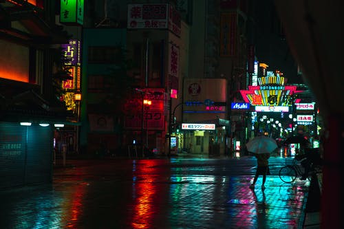 无法识别人在夜晚的亚洲城市湿的人行道上 · 免费素材图片