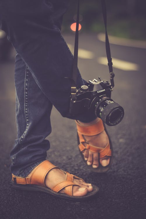 黑色cosina单反相机在白天挂在脚旁边 · 免费素材图片