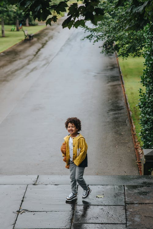 在城市公园的湿路面上行走的开朗民族男孩 · 免费素材图片