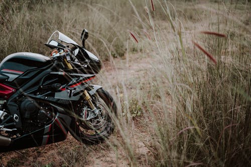 黑色和红色胜利代托纳摩托车停在棕色草地上的照片 · 免费素材图片
