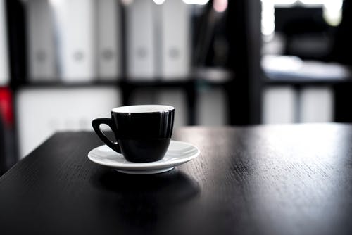 黑色和白色陶瓷茶杯与茶碟黑色木制的桌子上 · 免费素材图片