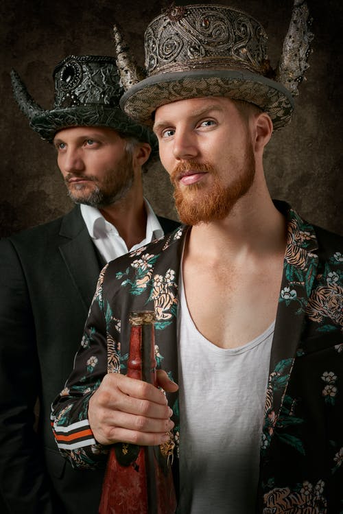 拿着棕色玻璃瓶的黑花衣服夹克的人 · 免费素材图片