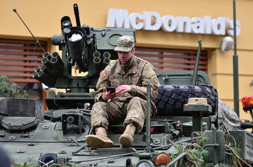 坐在坦克顶部的男士棕色和白色迷彩军装 · 免费素材图片