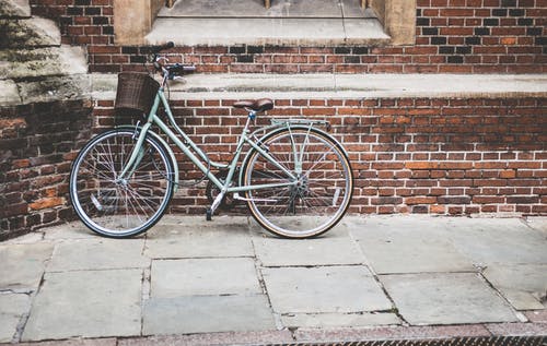 蓝色自行车停在棕色砖墙上 · 免费素材图片