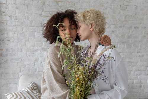 温柔的多种族妇女与野花拥抱在房间里 · 免费素材图片