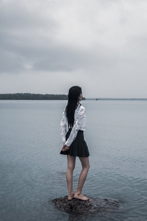 站在水面上的石头上的女人 · 免费素材图片