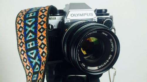 黑色和灰色olympus Dslr相机白色橙色蓝色和白色表带 · 免费素材图片