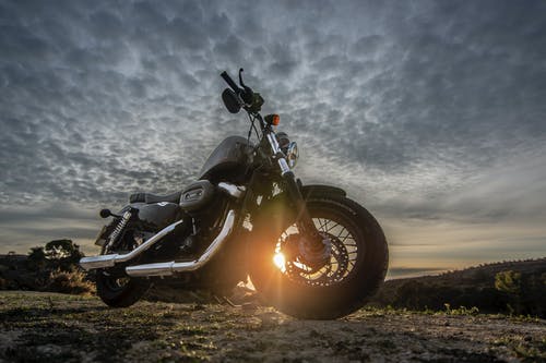 黑色哈雷戴维森四十八辆1200摩托车在黄金时段停在土路上的低角度照片 · 免费素材图片
