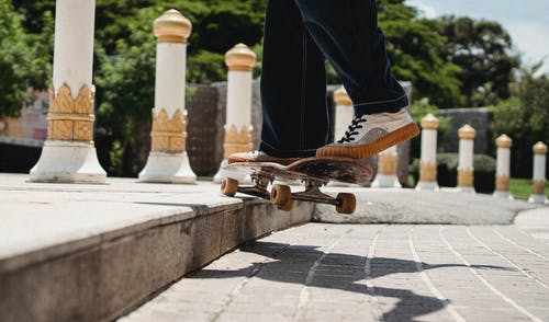 对城市公园的人行道上的作物运动员滑板 · 免费素材图片