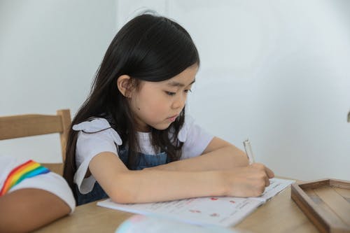 集中亚洲女学生做作业附近作物朋友在桌子上 · 免费素材图片