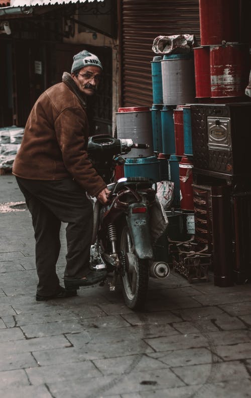站在摩托车旁边的棕色夹克的男人 · 免费素材图片