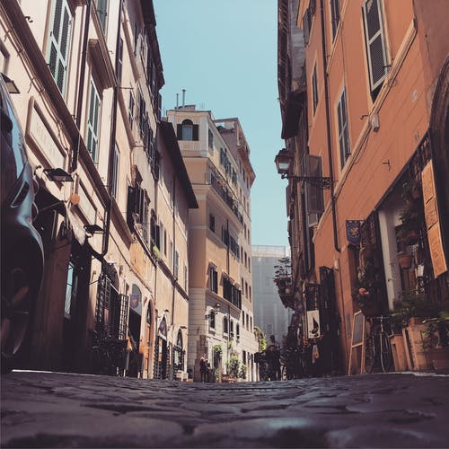 建筑物之间的鹅卵石街的低角度照片 · 免费素材图片