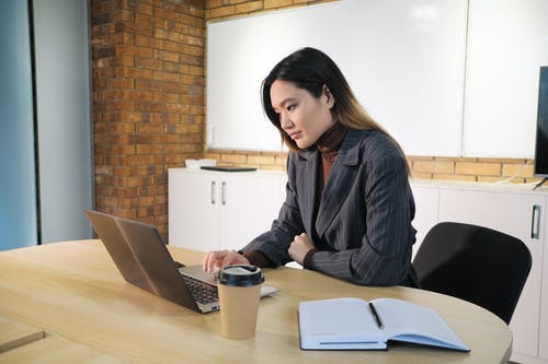 键入在膝上型计算机的亚裔女实业家在桌上在办公室 · 免费素材图片