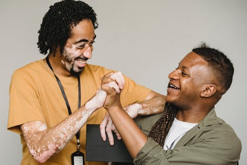笑黑人男性同事一起在兴奋中紧握双手 · 免费素材图片