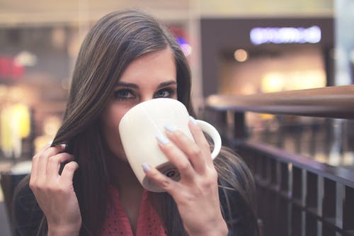 黑色睫毛膏在白色陶瓷杯上喝酒的女人 · 免费素材图片