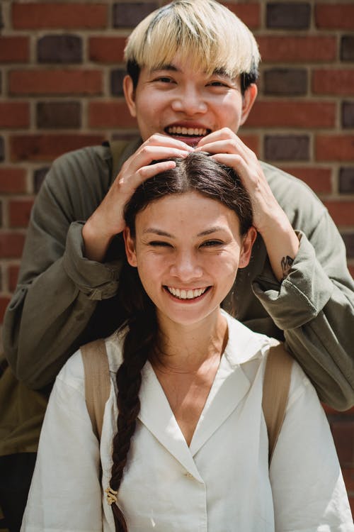 亚洲对幸福的夫妻，砖壁附近 · 免费素材图片