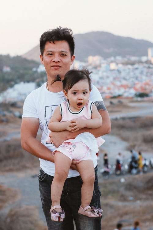 一名女婴的白领圆领t恤的男人 · 免费素材图片