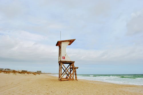 棕色木制救生塔在海滩上 · 免费素材图片