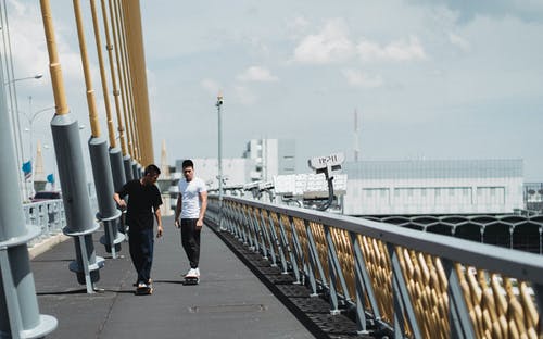 夏季在城市桥梁上滑板的族裔运动员 · 免费素材图片