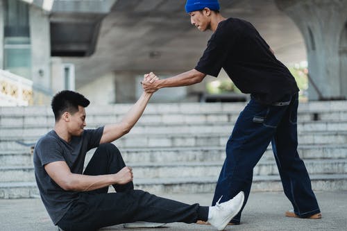 亚洲人帮助朋友从地面起床 · 免费素材图片