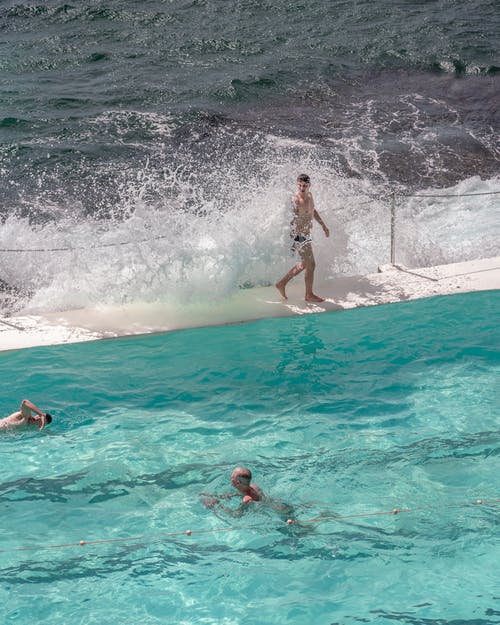 在池畔附近溅海水上行走的人 · 免费素材图片