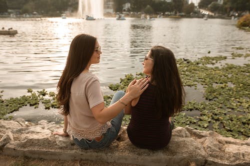 两个女人坐在湖边 · 免费素材图片