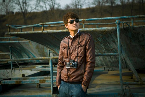 穿棕色皮夹克与黑色单反相机站在滑板公园选择性聚焦摄影的人 · 免费素材图片