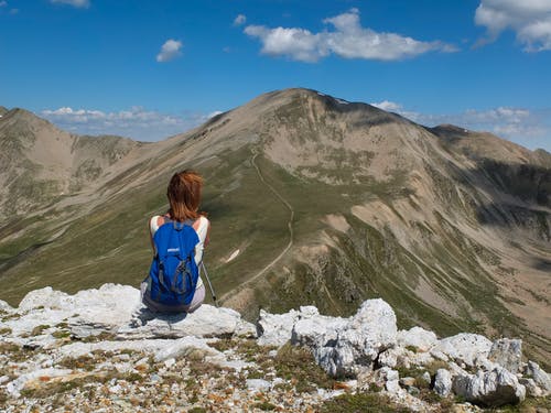 女人坐在山的岩石前面 · 免费素材图片