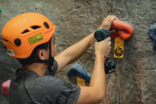 庄稼运动员用螺丝刀在健身房的墙壁上紧固攀登举行 · 免费素材图片