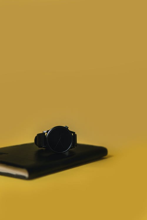 一本书上的圆形黑色模拟手表 · 免费素材图片