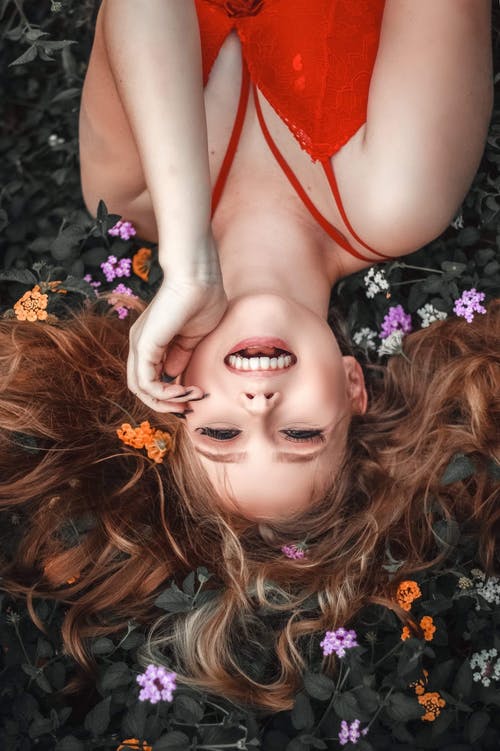 女人穿着红色背心躺在叶子上 · 免费素材图片