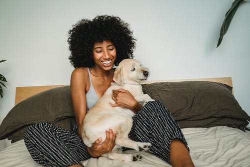 有狗的微笑的黑人妇女在床上 · 免费素材图片
