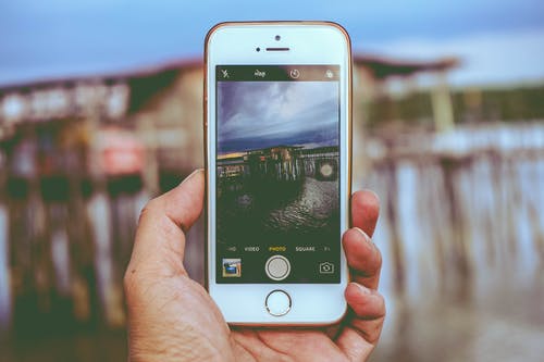 图片持有iphone拍照在海滩上的房子 · 免费素材图片