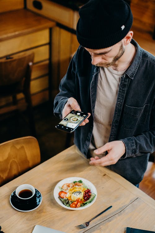 男人在桌子上拍他的早餐和咖啡的照片 · 免费素材图片