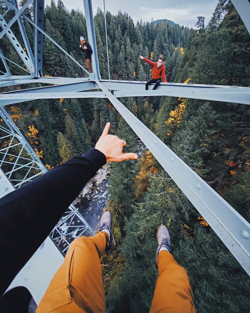 黑裤子和棕色的鞋子，站在白色金属桥上的人 · 免费素材图片