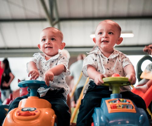 两个婴儿坐在玩具车上的照片 · 免费素材图片
