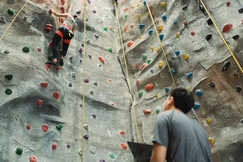 在锻炼过程中匿名教练和登山者登高人造岩石 · 免费素材图片