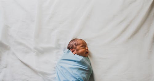 用蓝色毯子盖着的新生婴儿的照片 · 免费素材图片