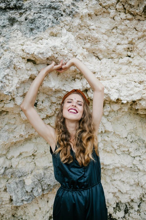 站立反对石形成的时髦的快乐的妇女 · 免费素材图片