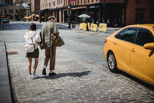 匿名的夫妇，在晴朗的一天在大街上抓出租车 · 免费素材图片