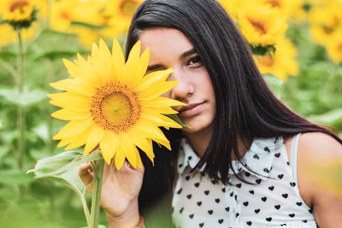 拿着向日葵的白色和黑色的圆点衬衫的女人 · 免费素材图片