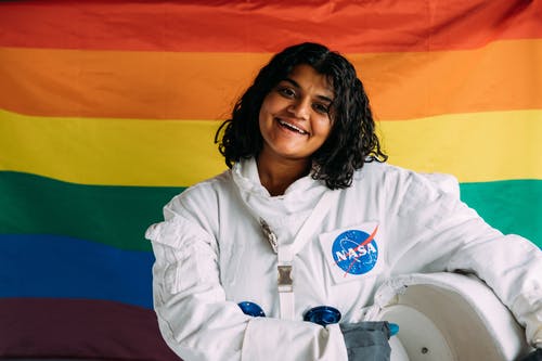 微笑的女士站在一面五颜六色的彩旗 · 免费素材图片